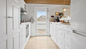 A narrow kitchen with white cabinetry, a wooden ceiling, and a view through an open door to the outside. - Awesome home in Thisted with sauna (Thisted)