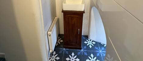 A small bathroom with a white sink, wooden cabinet, and a radiator.
