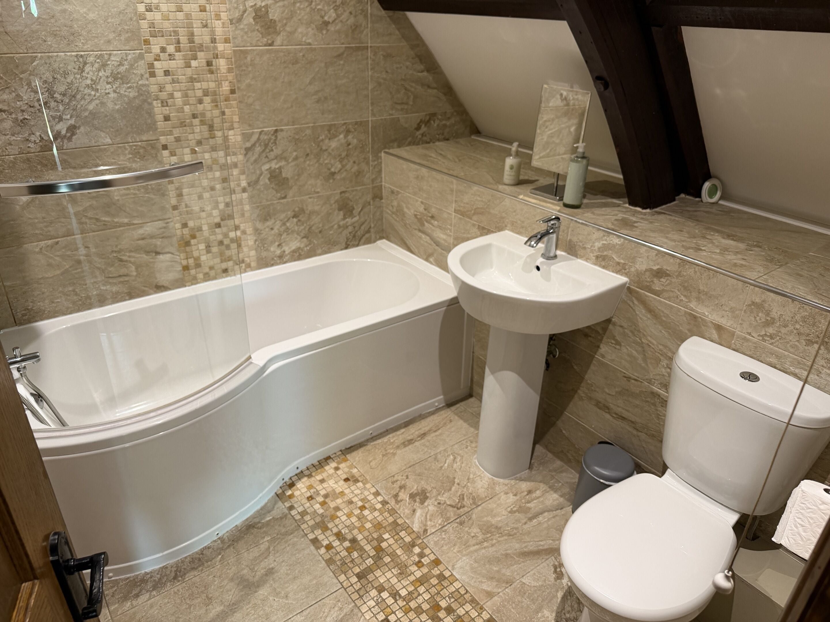 Un bagno con vasca, lavandino, WC e pavimento piastrellato.