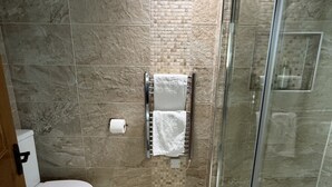 Een badkamer met toilet, douche met glazen deur en betegelde vloer.