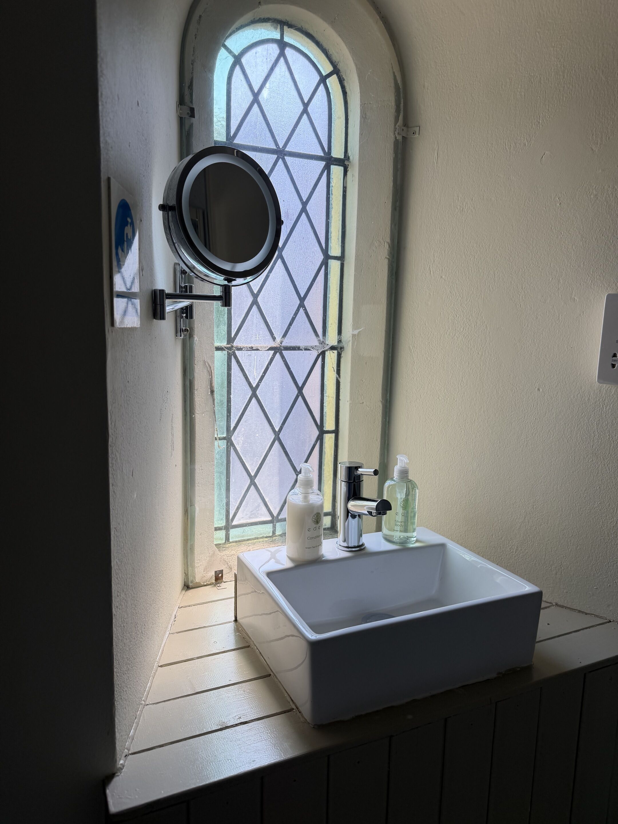 Een badkamer met een witte wastafel, een spiegel en twee flessen shampoo.