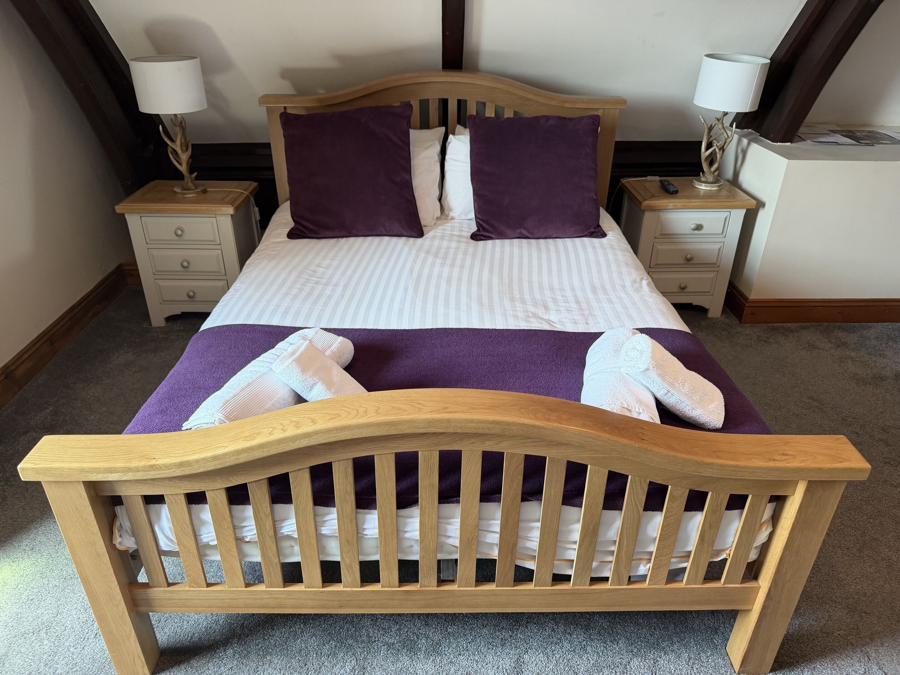 A bed with a wooden headboard, two nightstands with lamps, and a purple throw blanket.