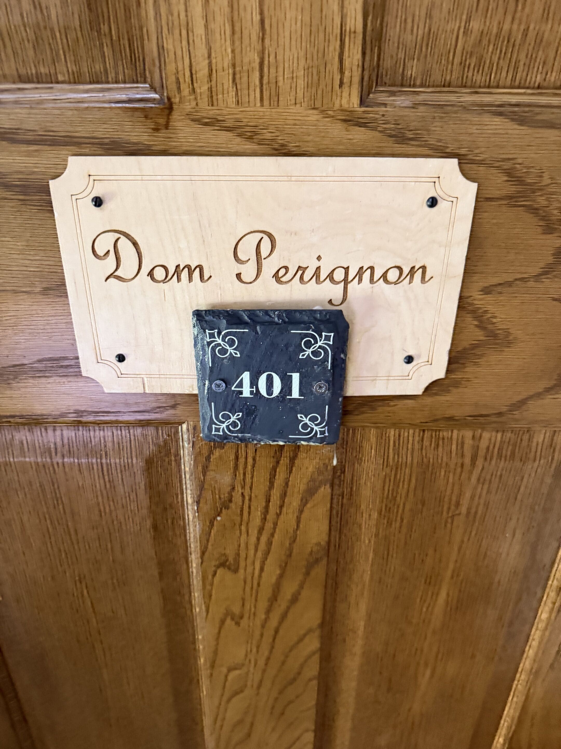 A wooden door with a nameplate reading 'Dom Perignon' and a small black plaque with the number '401'.