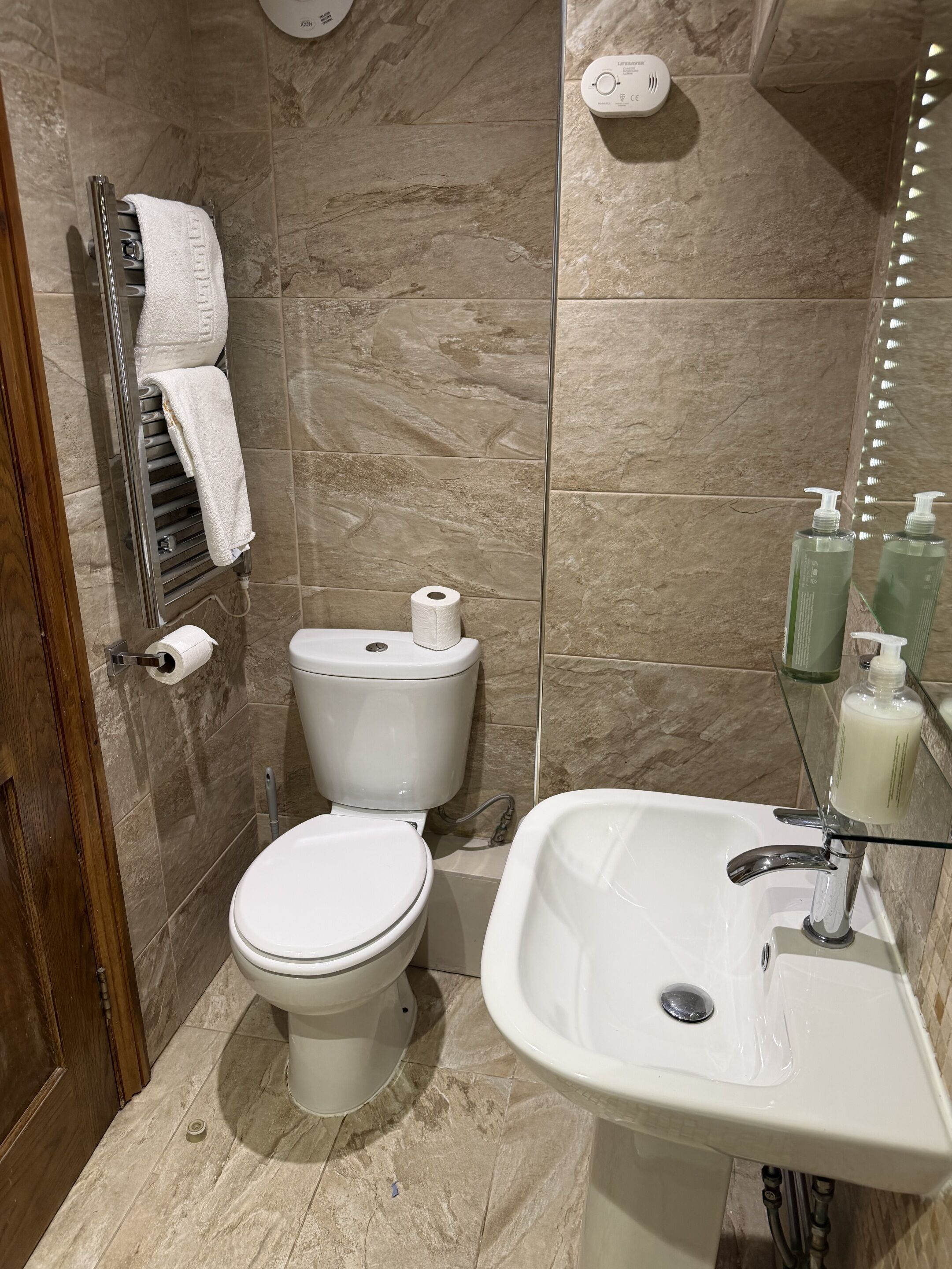 Une salle de bain équipée de toilettes, d’un lavabo et d’un porte-serviettes.