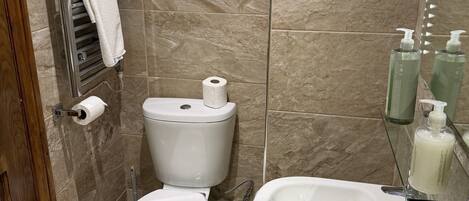Une salle de bain équipée de toilettes, d’un lavabo et d’un porte-serviettes.