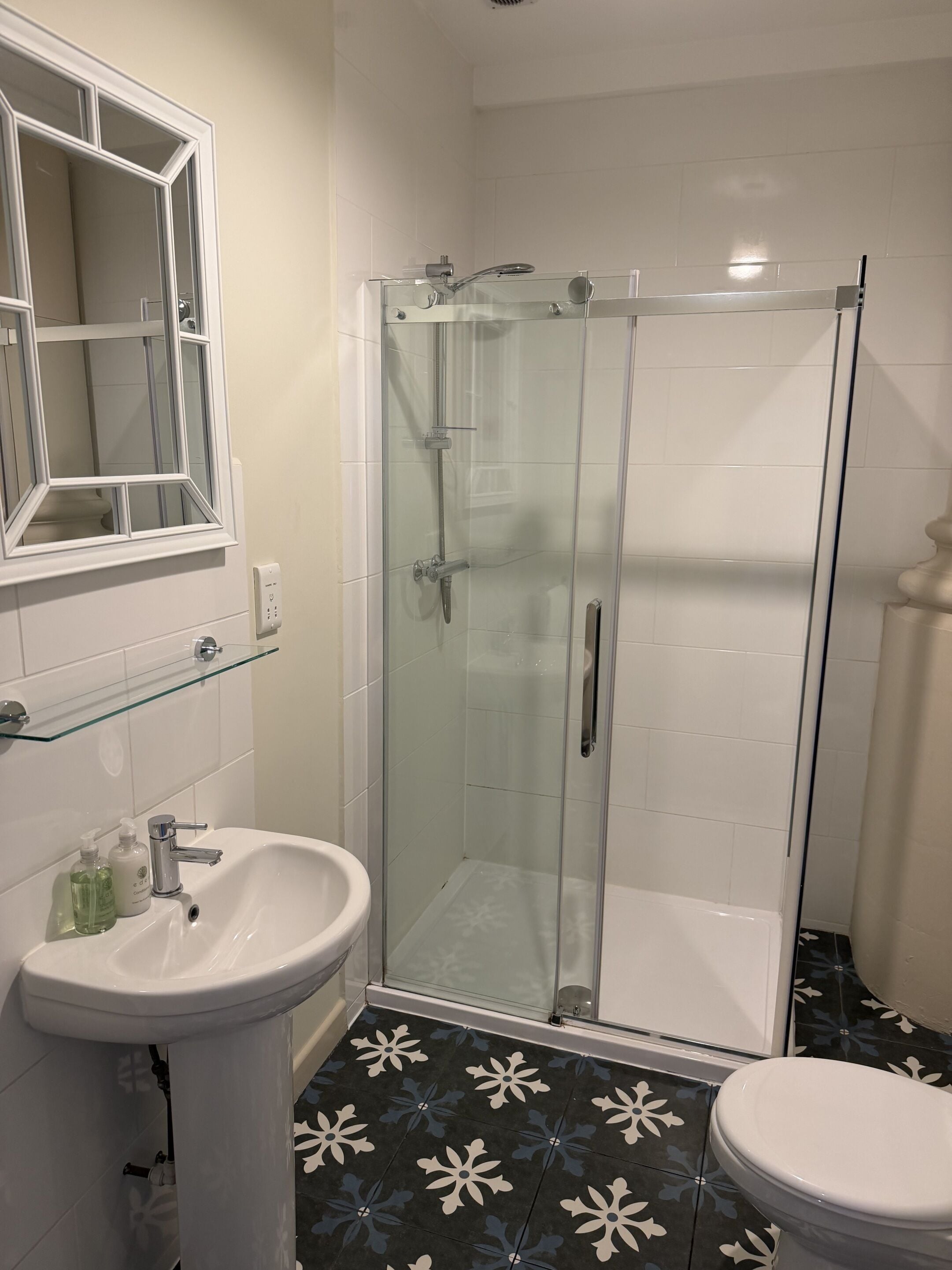 A bathroom with a glass-enclosed shower, a white sink, and a toilet.