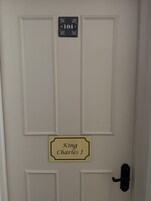 Una puerta con una placa que indica '104' y un cartel debajo que dice 'Carlos I'.