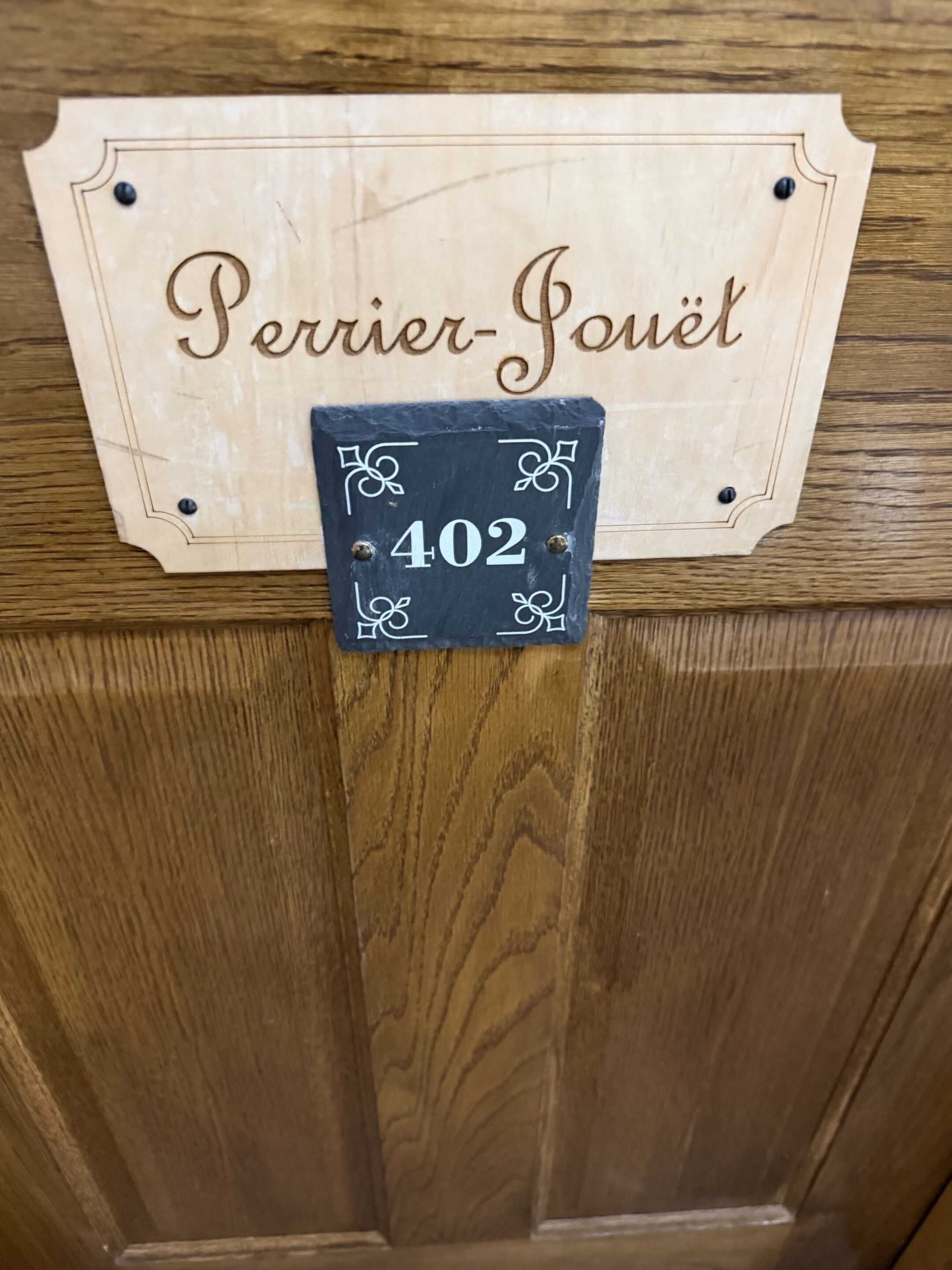 A wooden door with a sign that reads 'Perrier-Jouët' and a smaller sign below it with the number '402'.