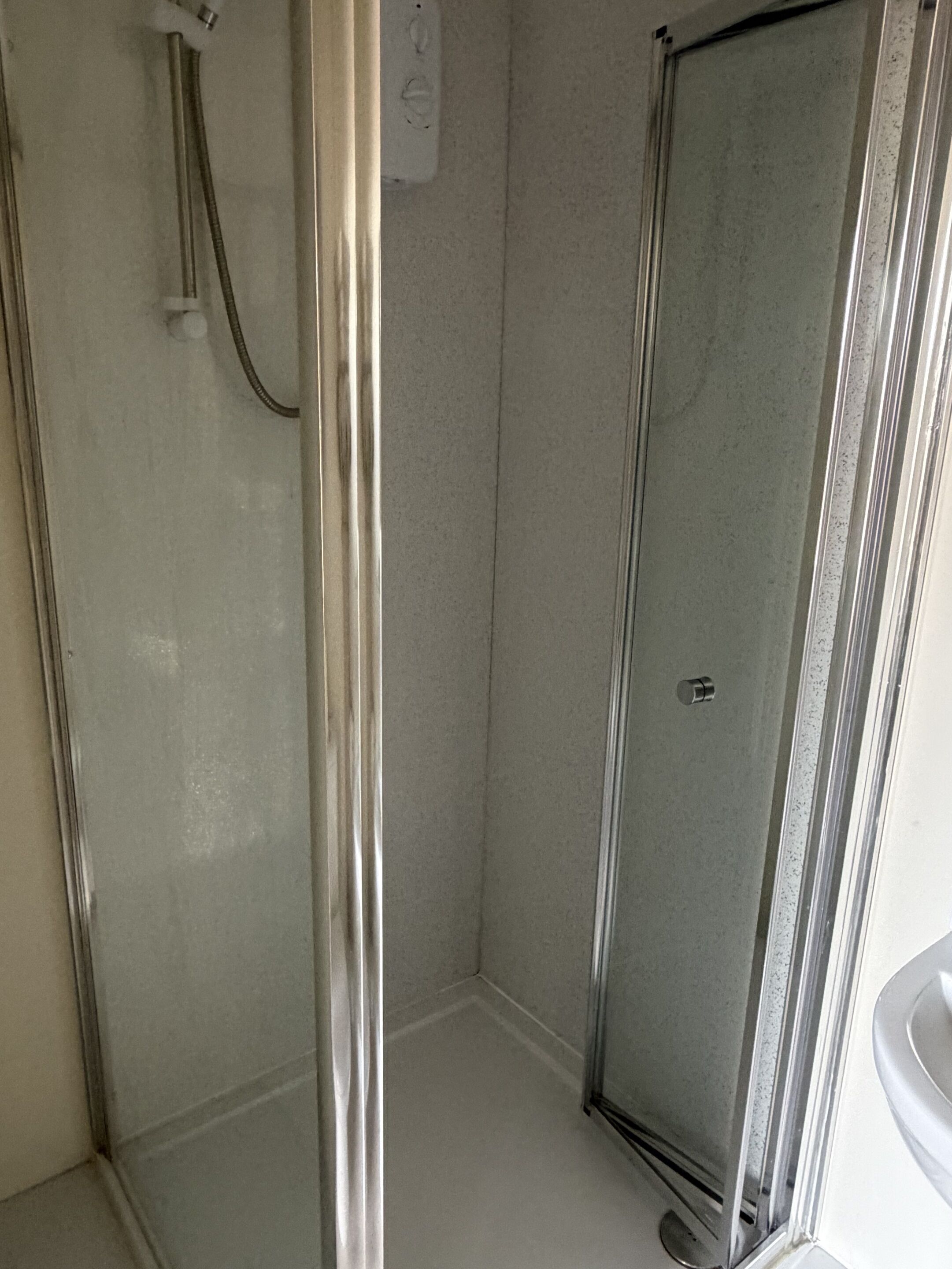 Un bagno con box doccia in vetro, un water e un lavandino.