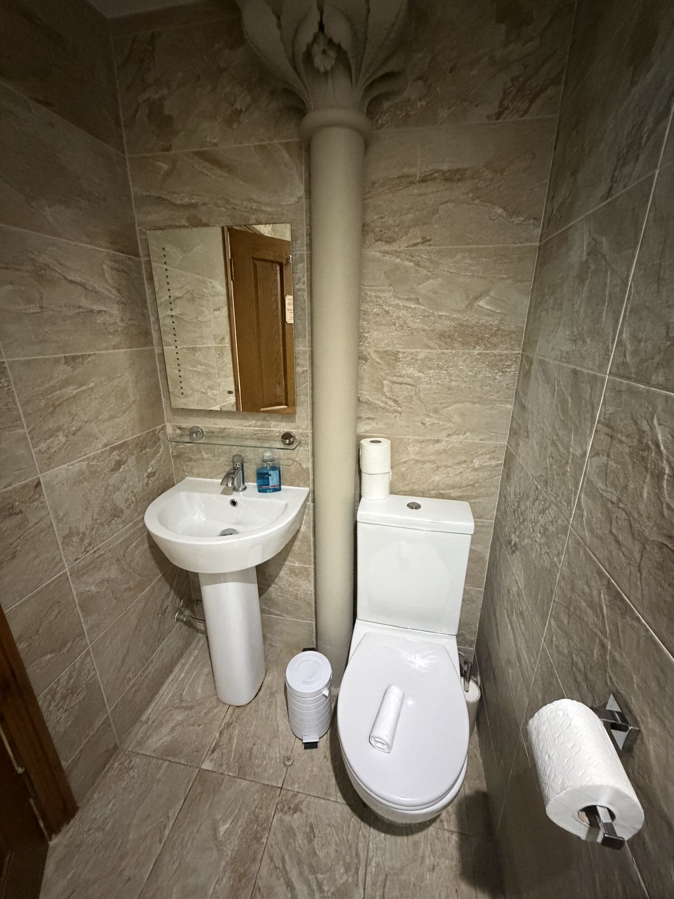 Et badeværelse med et konsolbord, toilet og et spejl over vasken.