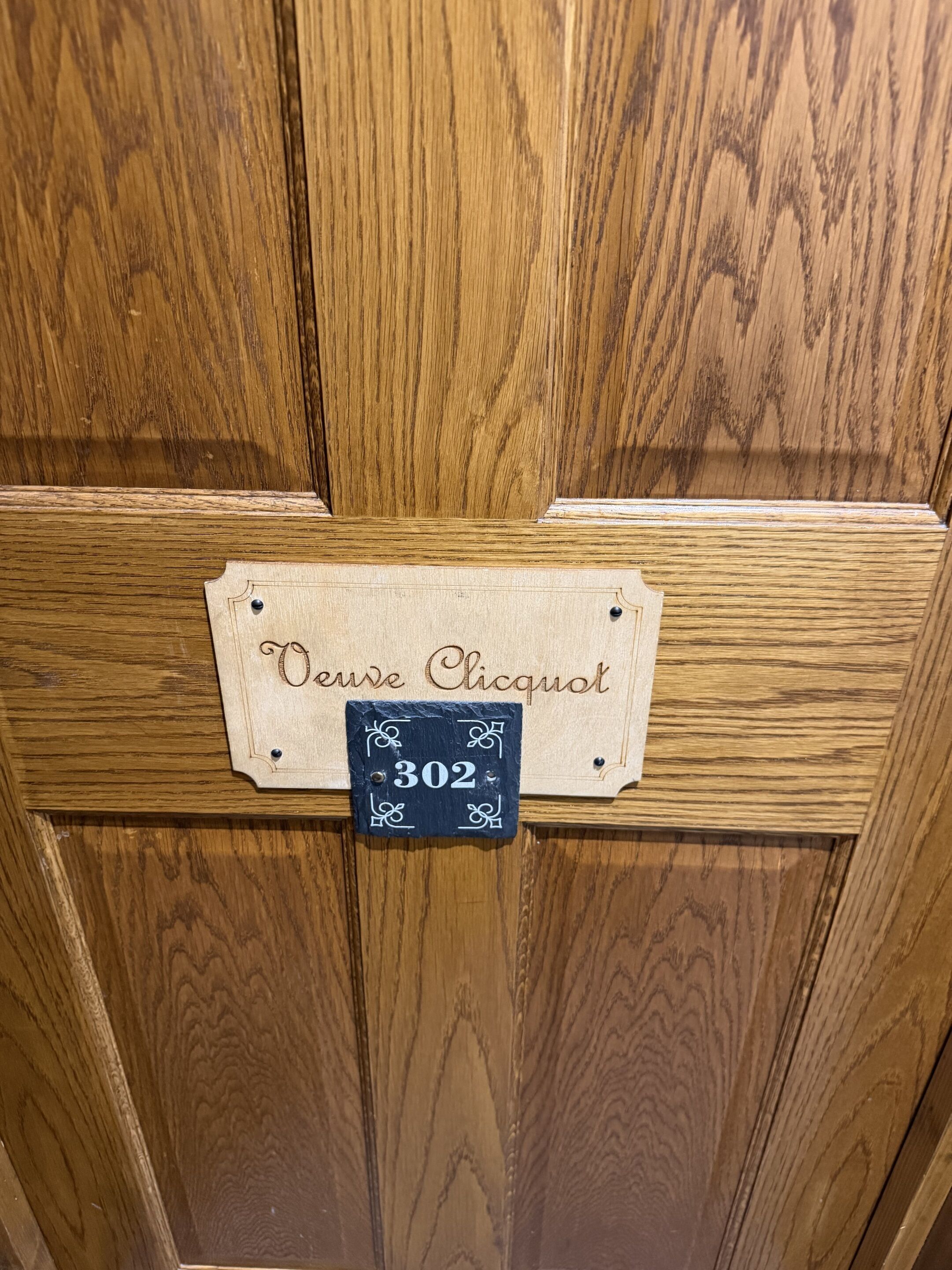 A wooden door with a sign that reads 'Oeuvre Clicquot' and a number '302'.