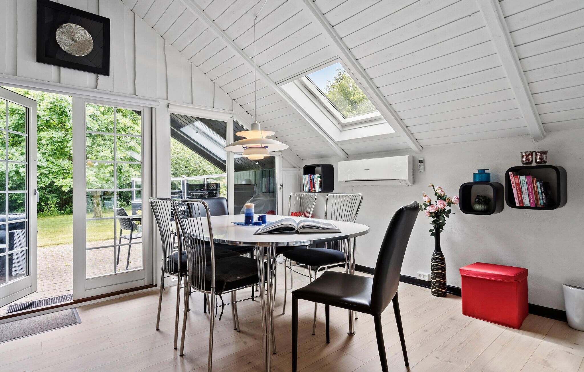 A modern dining area with a round table, chairs, and a skylight.