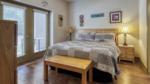 A bedroom with a large bed, a wooden bench, a nightstand, and a wall with decorative items. - Fantastic and Convenient Smoky Mountain View Condo! 2104 (Pigeon Forge)