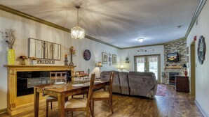 A dining area with a wooden table and chairs, a chandelier, and a fireplace. - Fantastic and Convenient Smoky Mountain View Condo! 2104 (Pigeon Forge)