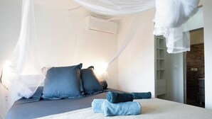 A bedroom with a bed, pillows, a white canopy, and a white air conditioning unit. - Tropical escape in an authentic Creole villa with private saltwater pool. (Anse-Bertrand)