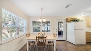A kitchen with a dining table, chairs, a refrigerator, and a window with blinds. - Lakefront home on Lake Kerr near Salt Springs with large porch and great yard (Salt Springs)