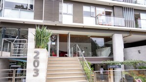 A modern building with a staircase leading to an entrance, a large potted plant, and a sign with the number 203. - Redibuk - Nice 1BR apartment in Barranco (Lima)