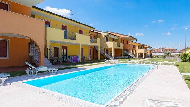 A swimming pool with lounge chairs, a staircase, and a building with balconies. - La Mimosa B03 Apartment by Wonderful Italy (Peschiera del Garda)