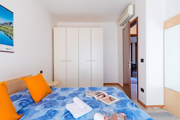 Una habitación de hotel con una cama, un armario, una puerta y un equipo de aire acondicionado.