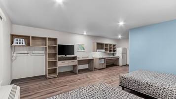 Una habitación moderna y luminosa, con escritorio, computadora, televisión y kitchenette.