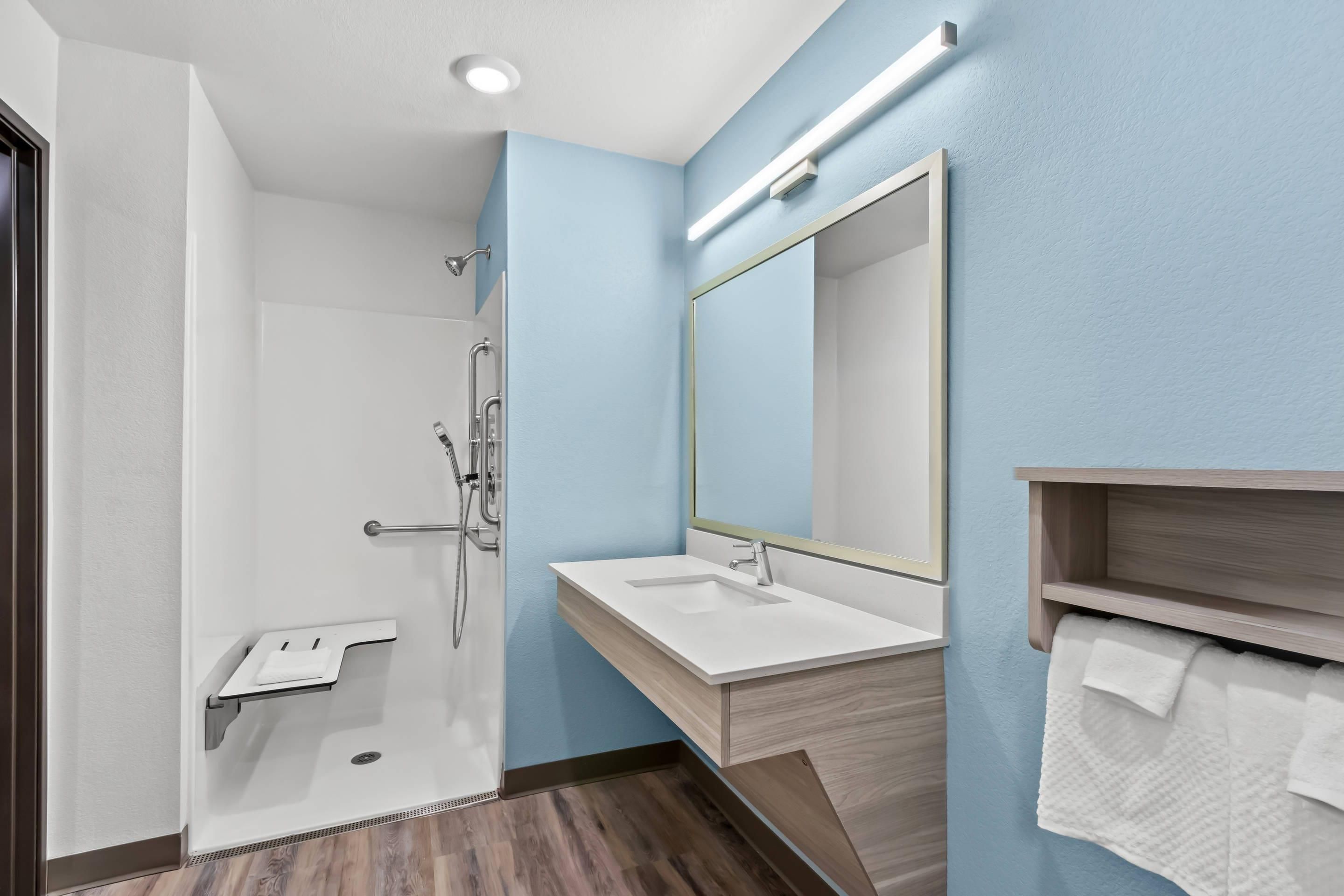 A modern bathroom with a shower, sink, and mirror.