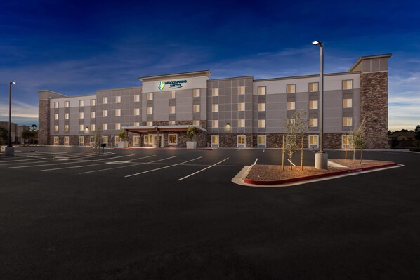 A multi-story hotel with a flat facade, a central entrance, and a parking lot. - Woodspring Suites Gilbert - Mesa Gateway Airport (Gilbert)