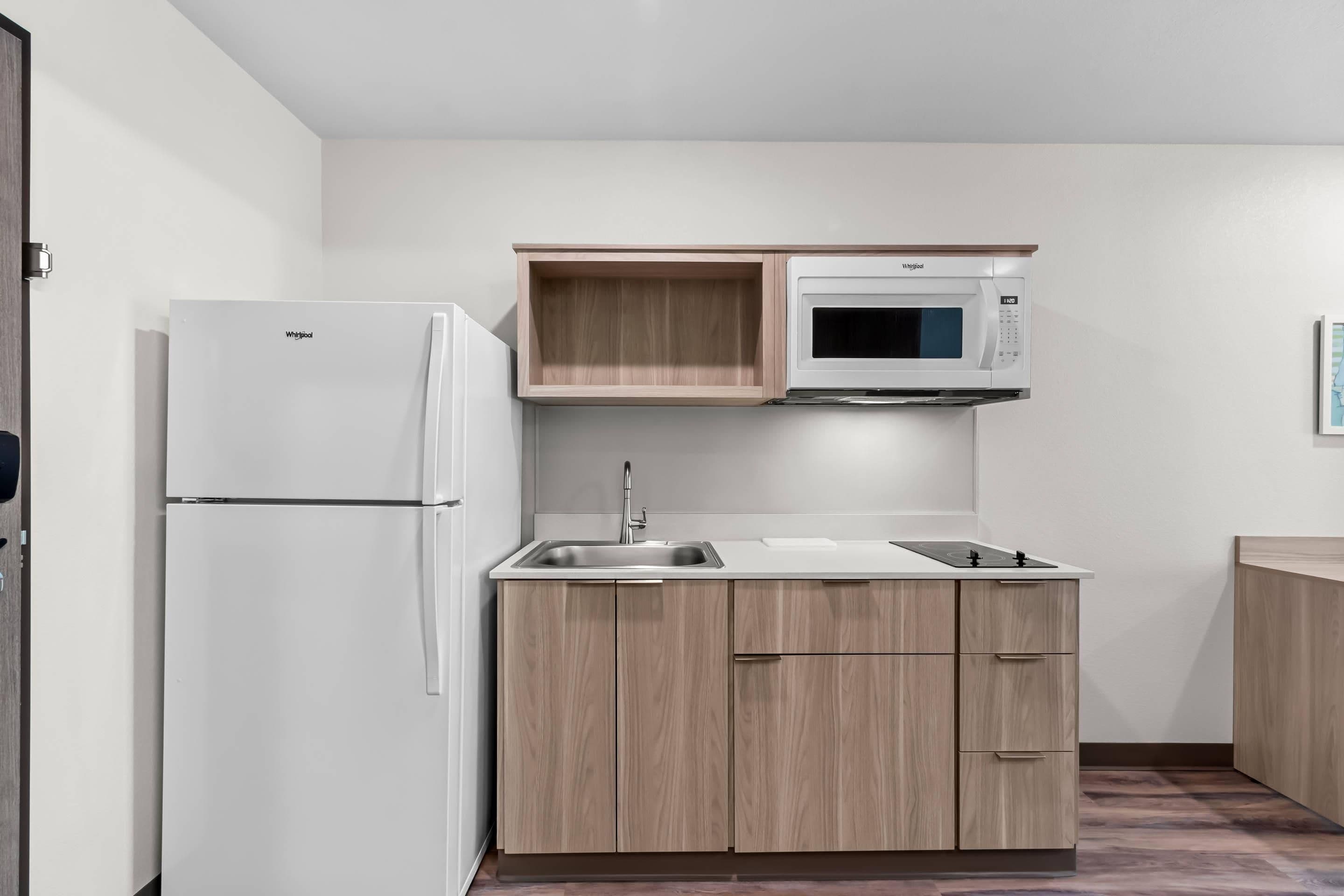 Una cocina compacta con refrigerador integrado, microondas y pileta.