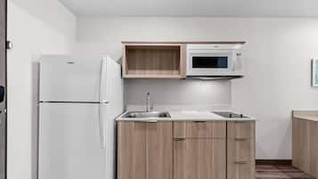 Una cocina compacta con refrigerador integrado, microondas y pileta.