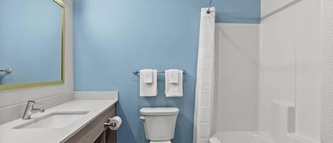 A bathroom with a white toilet, a sink, a mirror, and a shower curtain.