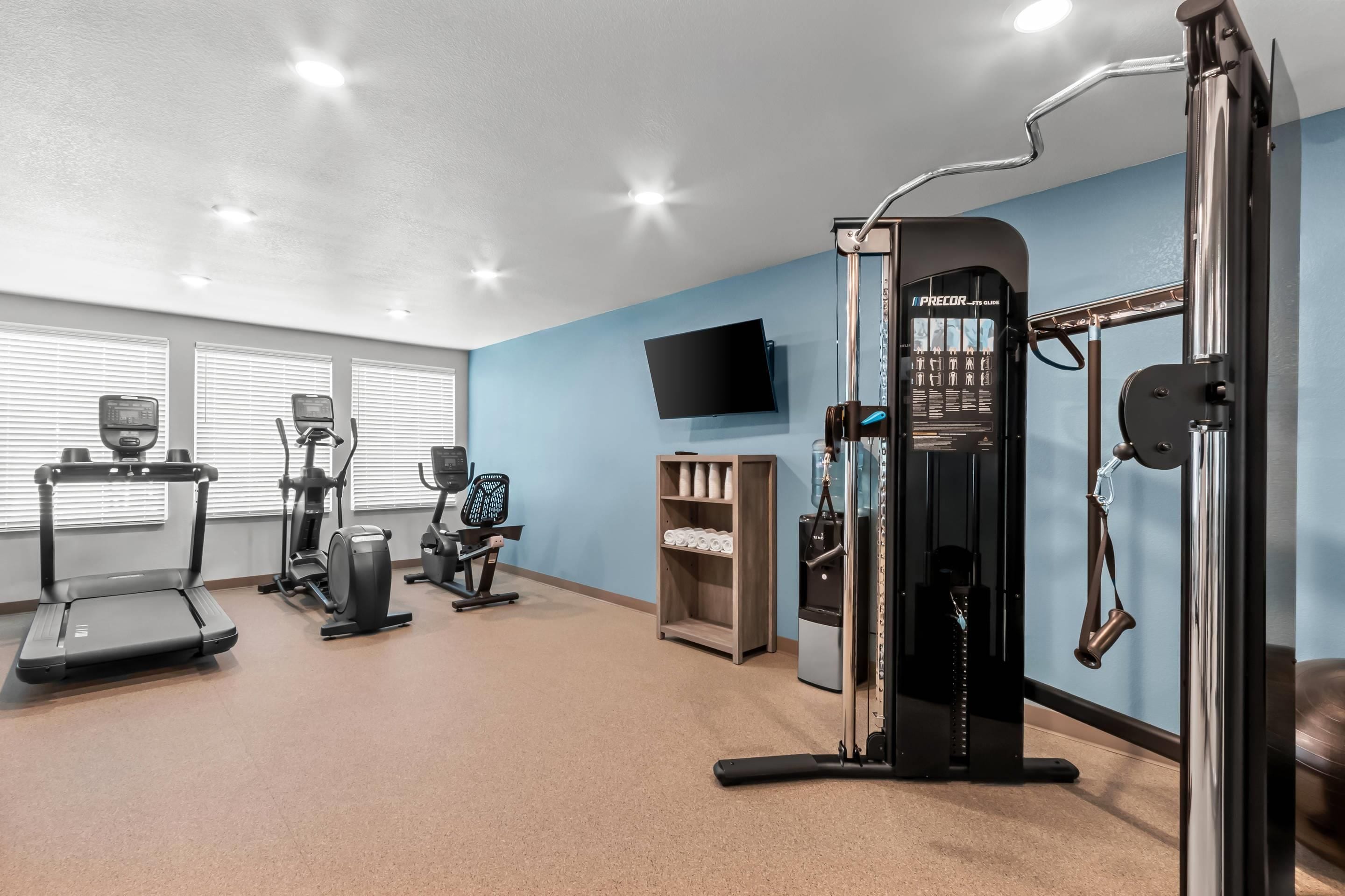 A home gym with exercise equipment, a water dispenser, and a TV on the wall.