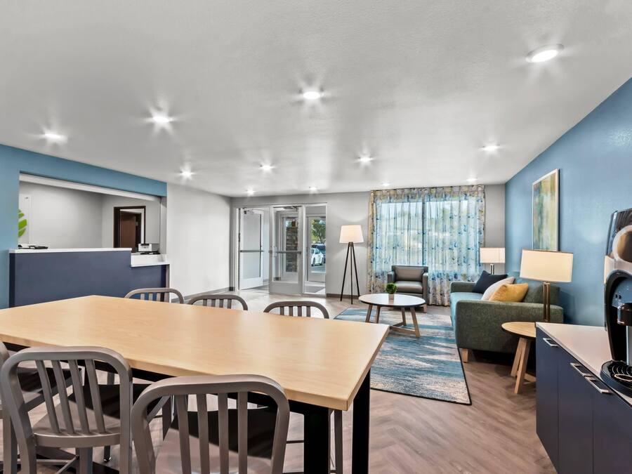 A modern hotel room with a dining area, a sofa, and a TV.
