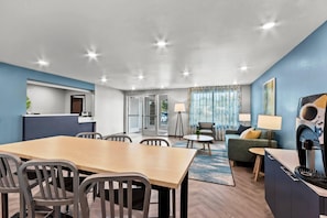 A modern hotel room with a dining area, a sofa, and a TV. - Woodspring Suites Gilbert - Mesa Gateway Airport (Gilbert)
