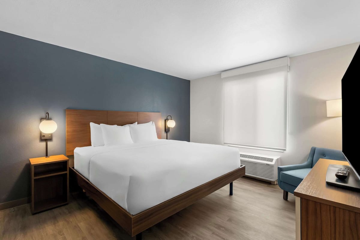 Una habitación de hotel con una cama grande, lámparas de noche, un escritorio y una silla.