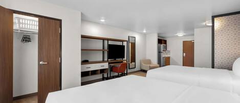 A hotel room with a bed, a desk, a chair, a wardrobe, and a television.