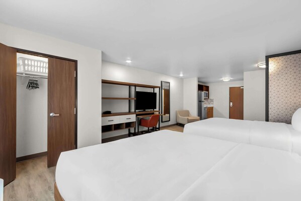 Una habitación de hotel con cama, escritorio, silla, armario y televisor.
