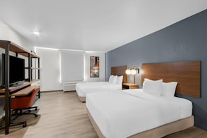 Une chambre d’hôtel avec deux lits, un bureau avec une télévision et une œuvre d’art accrochée au mur.