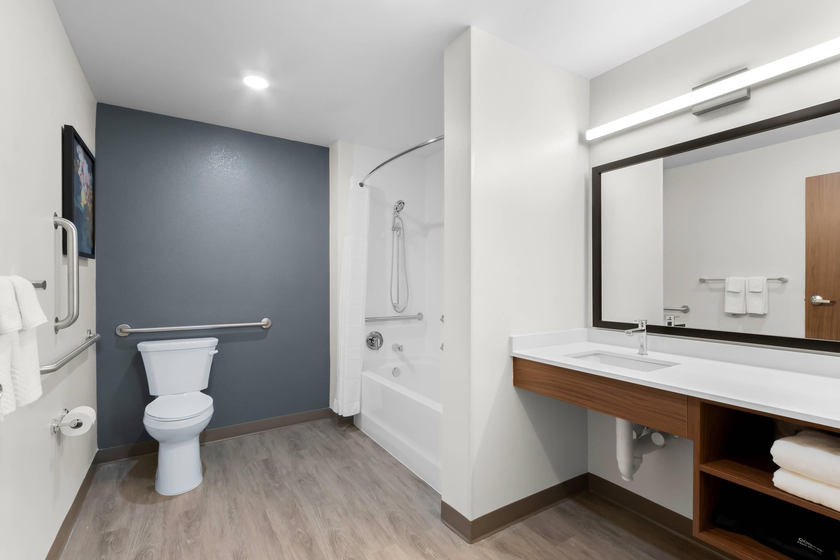 A modern bathroom with a toilet, shower, and sink.