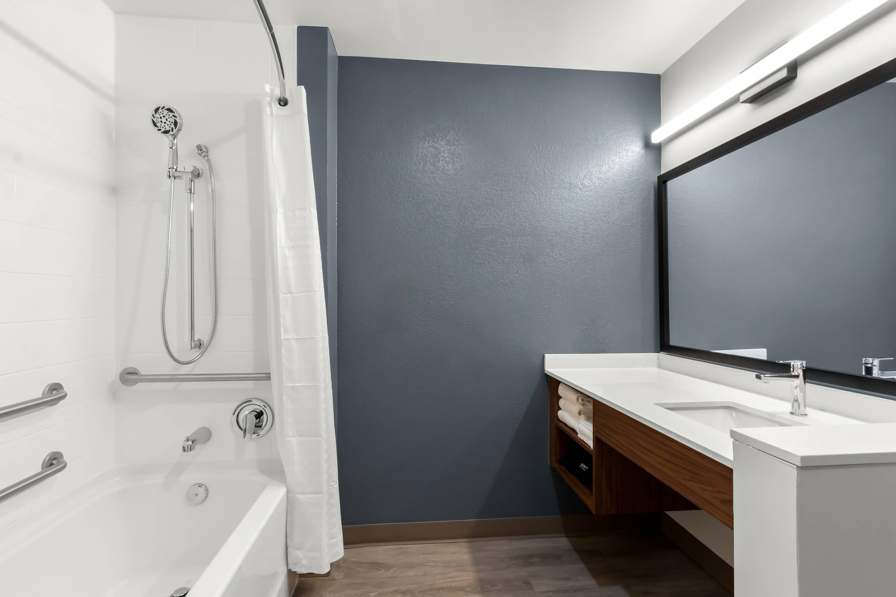A modern bathroom with a bathtub, shower, and a vanity with a mirror.