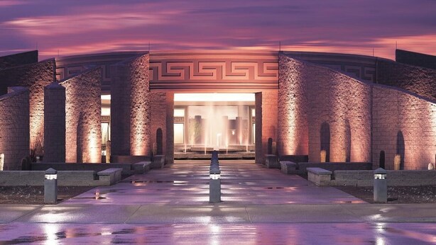 A building entrance with a geometric pattern, columns, and a reflective floor.