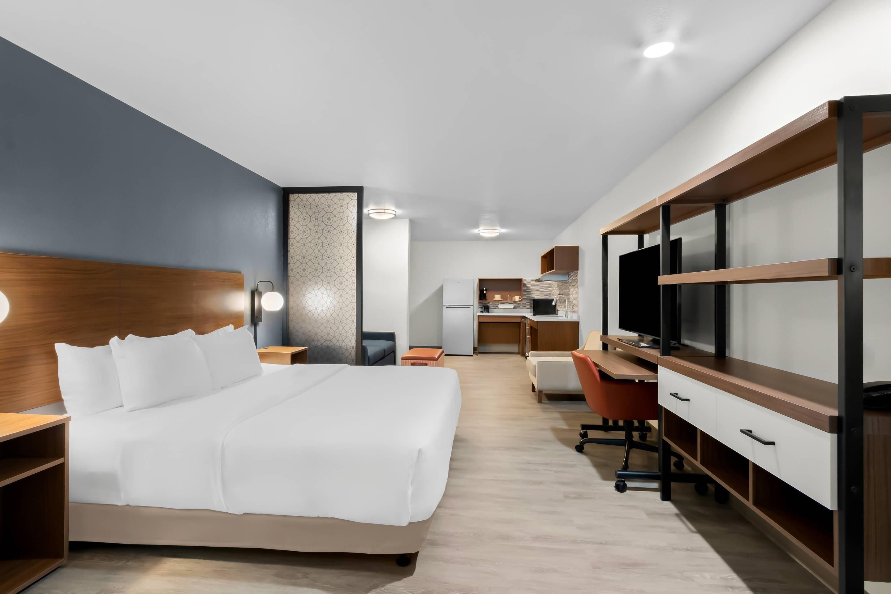 Una habitación de hotel moderna con cama, escritorio, silla y televisión.