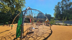 Une aire de jeux avec une structure d’escalade, des balançoires et un bac à sable.
