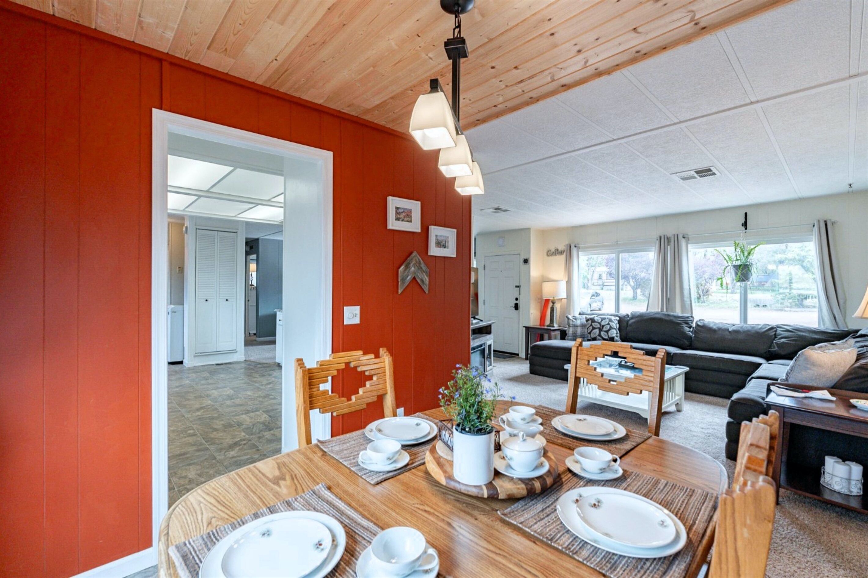 A dining area with a wooden table set for four, a sofa, and a view of the outdoors.