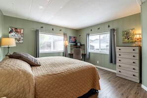 Une chambre à coucher comprenant un lit, une commode, un bureau, une chaise et des fenêtres.