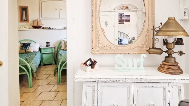 Une chambre avec un lit, une commode, un miroir et une lampe.