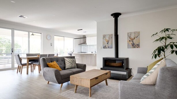 Ein modernes Wohnzimmer mit Kamin, grauen Sofas, einem Holztisch und einem Essbereich mit Stühlen und Tisch.