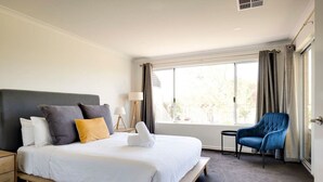 Ein Hotelzimmer mit einem Bett, einem Sessel, einer Lampe und einem Fenster.
