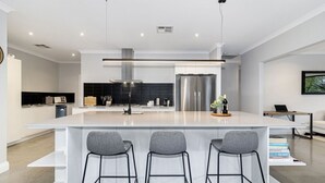 Una cocina moderna con una isla central, taburetes de bar y electrodomésticos de acero inoxidable.