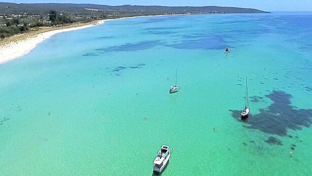 Una zona costera con aguas turquesas cristalinas, varios barcos y una playa de arena.