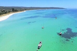 Una zona costera con aguas turquesas cristalinas, varios barcos y una playa de arena.
