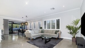 Una sala de estar moderna con un sofá modular, una mesa de centro de vidrio y un televisor de pantalla plana.